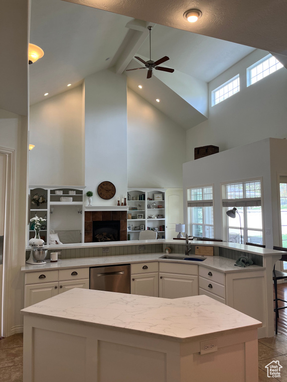 Kitchen with beam ceiling, sink, a fireplace, stainless steel dishwasher, and white cabinetry