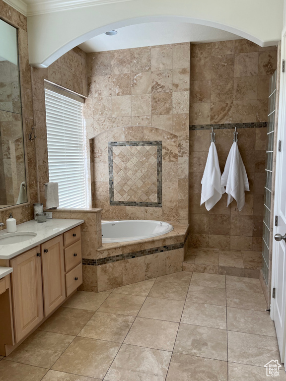 Bathroom featuring tile flooring, a relaxing tiled bath, vanity, and crown molding