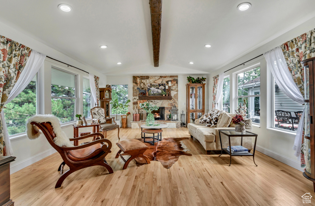 Living room with lofted ceiling with beams, light hardwood / wood-style floors, and a fireplace