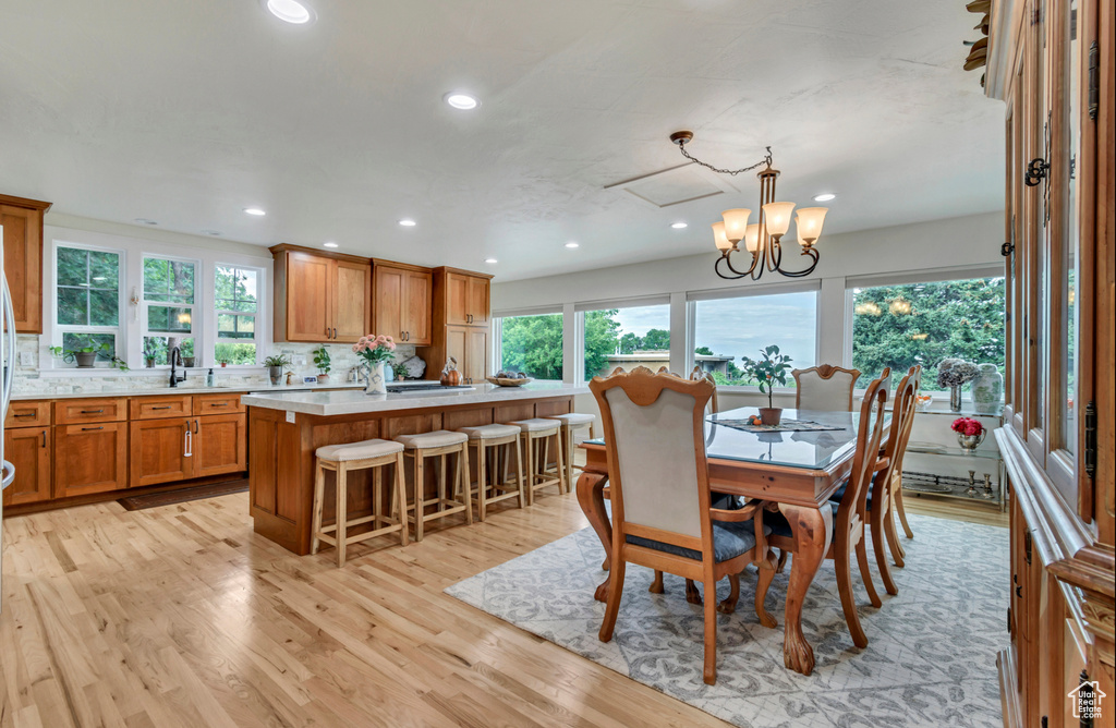 Dining space with a notable chandelier, plenty of natural light, light hardwood / wood-style floors, and sink
