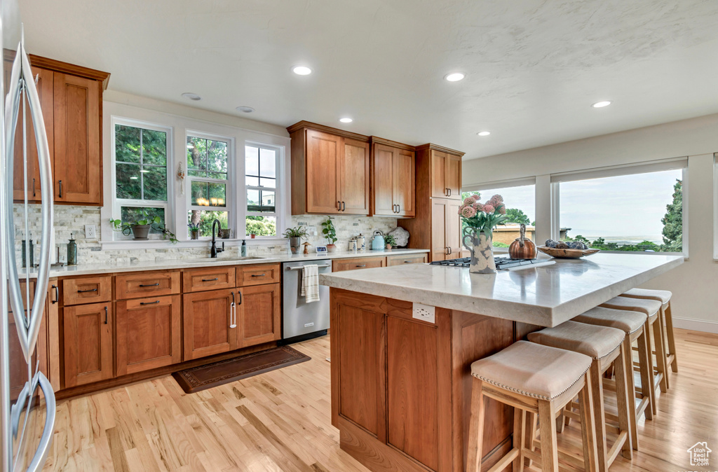 Kitchen with tasteful backsplash, stainless steel appliances, sink, and light hardwood / wood-style flooring