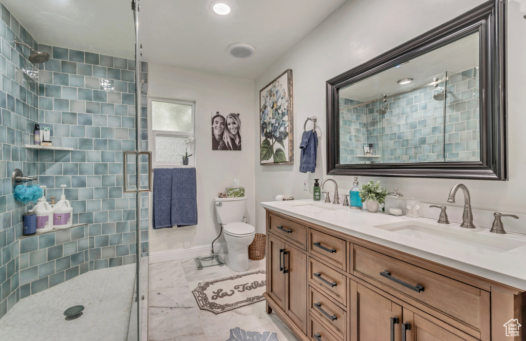 Bathroom with toilet, an enclosed shower, dual sinks, tile flooring, and oversized vanity