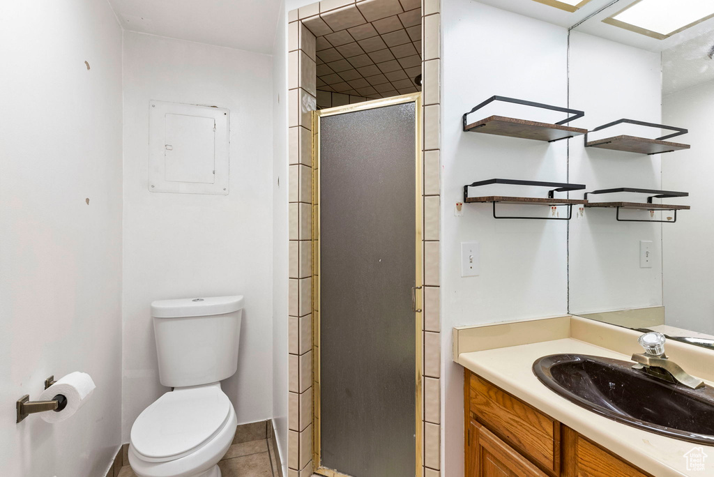Bathroom featuring toilet, tile flooring, a shower with shower door, and vanity