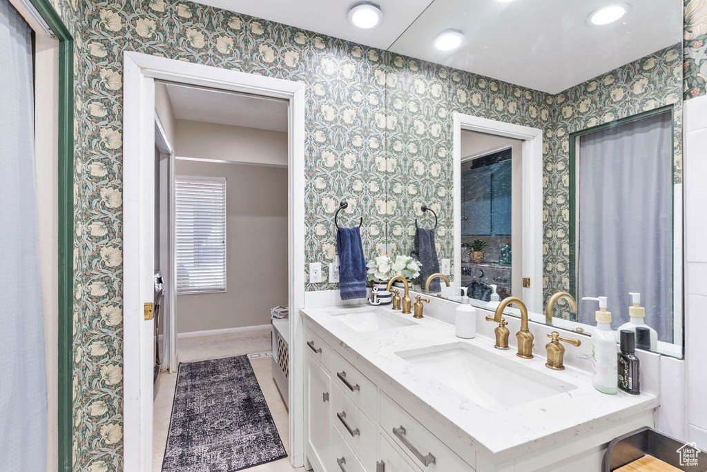 Bathroom featuring vanity with extensive cabinet space, tile flooring, and double sink