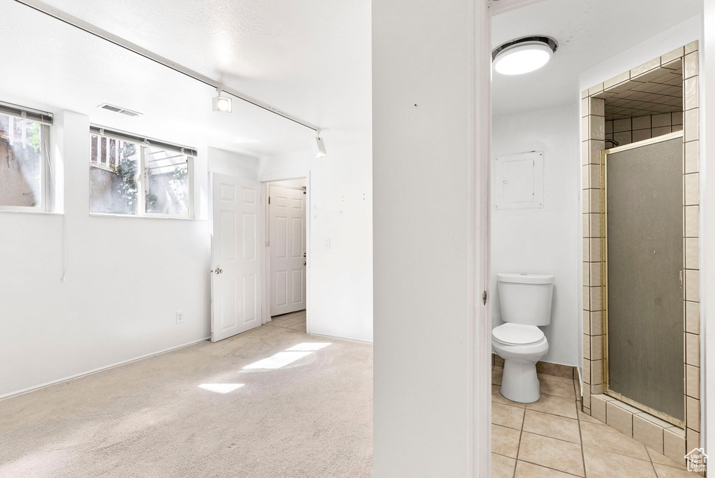 Bathroom with rail lighting, walk in shower, tile floors, and toilet