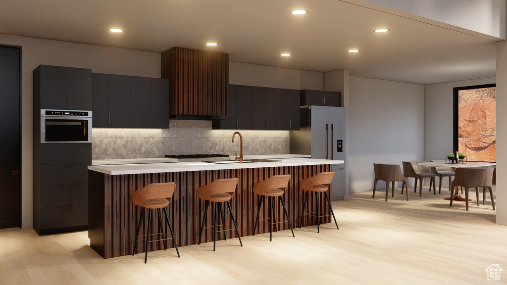Kitchen with a kitchen breakfast bar, tasteful backsplash, stainless steel appliances, and light wood-type flooring