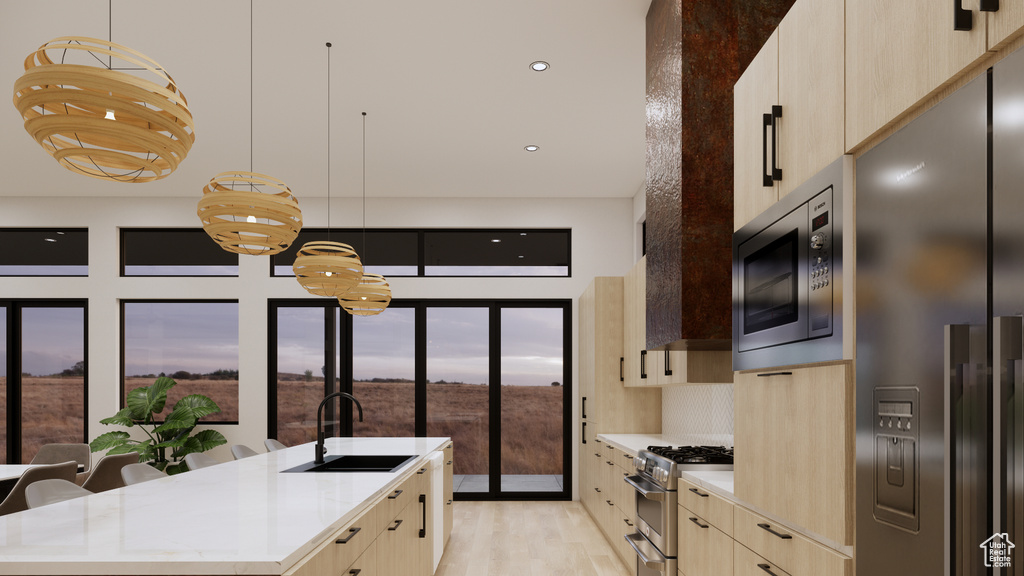 Kitchen featuring appliances with stainless steel finishes, modern cabinets, light brown cabinets, an island with sink, and light wood-style floors