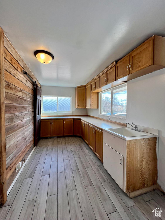 Kitchen featuring a barn door, light hardwood / wood-style floors, wooden walls, and sink