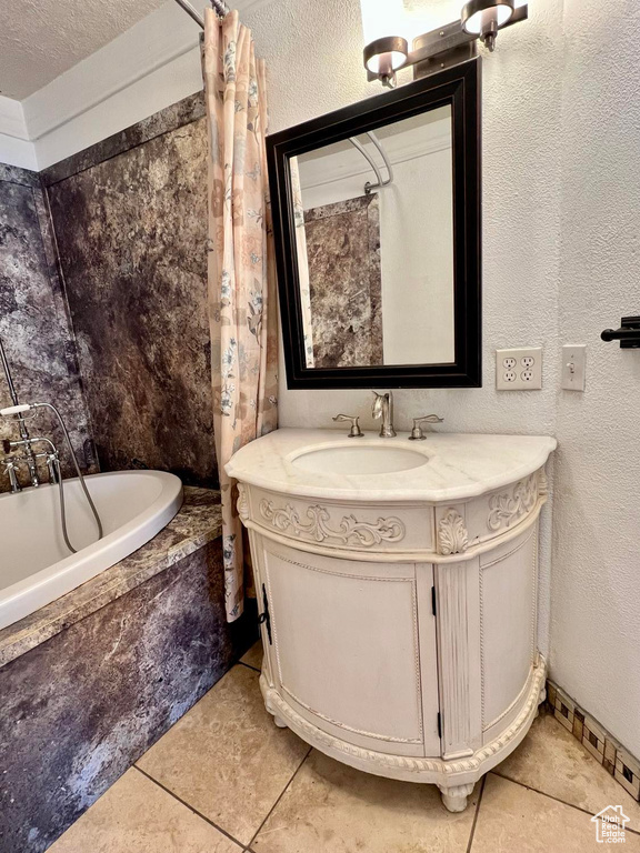 Bathroom with vanity, a textured ceiling, tile flooring, and tiled bath