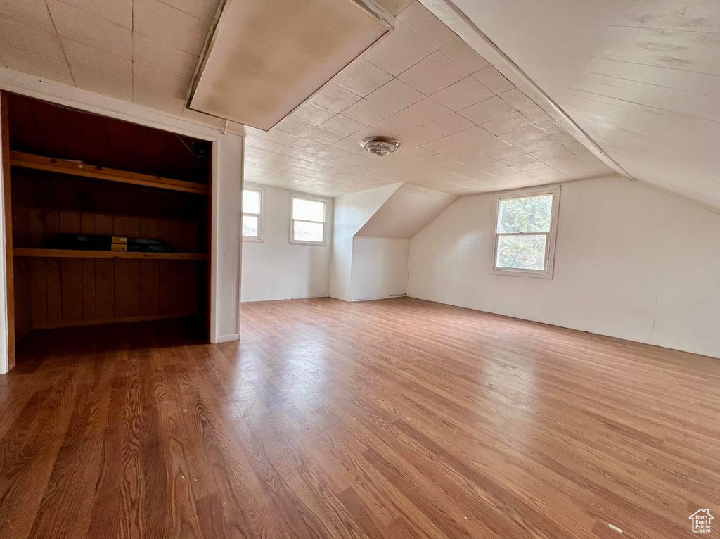 Bonus room featuring lofted ceiling, built in shelves, and wood-type flooring