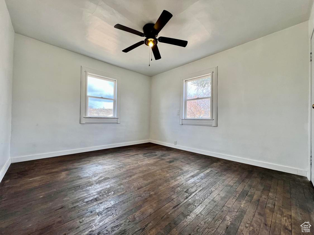 Empty room featuring plenty of natural light, dark hardwood / wood-style flooring, and ceiling fan