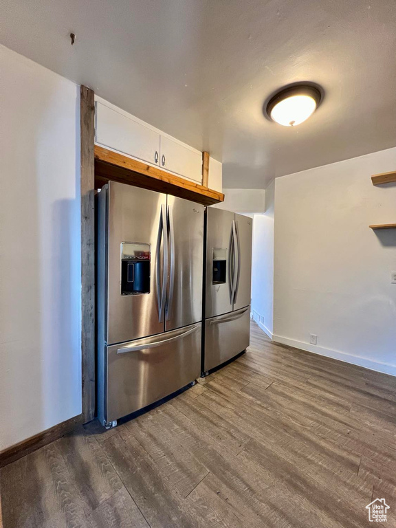 Kitchen featuring stainless steel fridge with ice dispenser, white cabinetry, and dark wood-type flooring