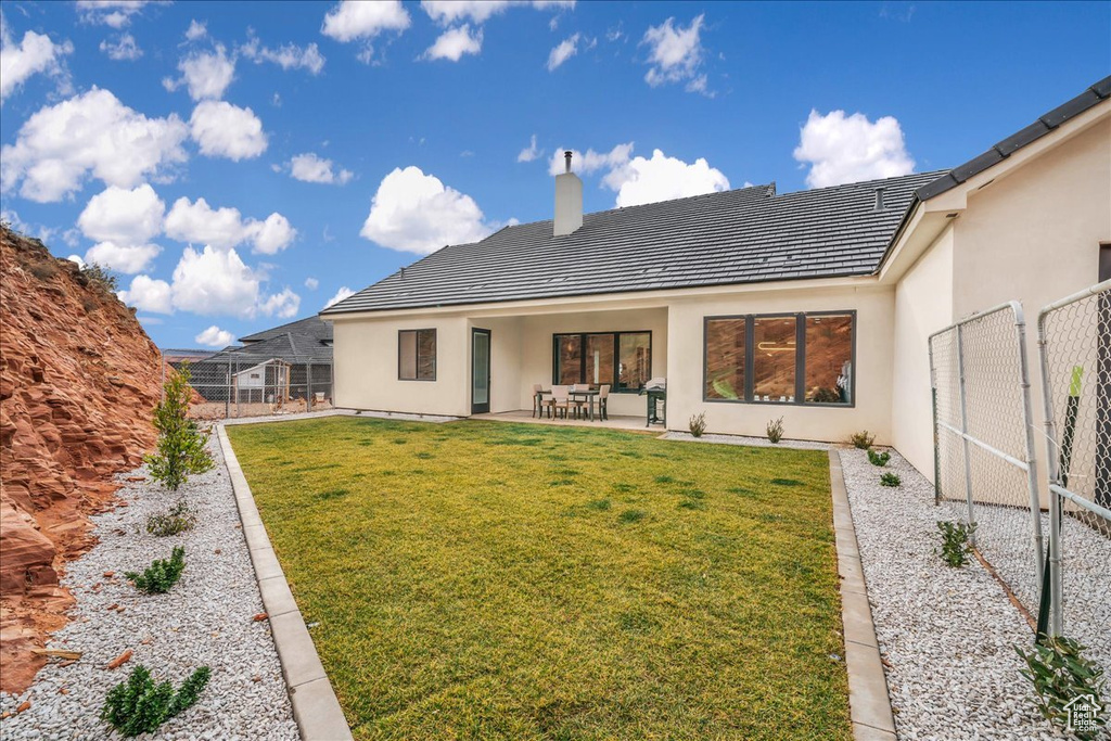 Rear view of house featuring a lawn and a patio