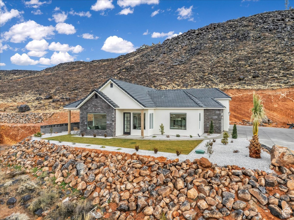 View of front of house featuring a front lawn, a patio area, and a mountain view