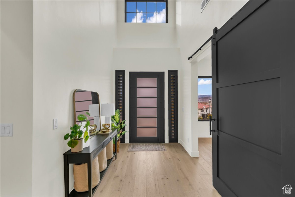 Entrance foyer with a high ceiling, a barn door, and light hardwood / wood-style flooring