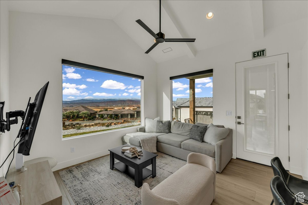 Living room with light hardwood / wood-style floors, ceiling fan, and high vaulted ceiling