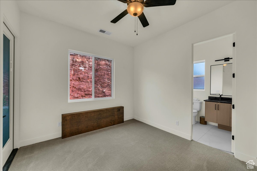 Empty room featuring light carpet, ceiling fan, and sink