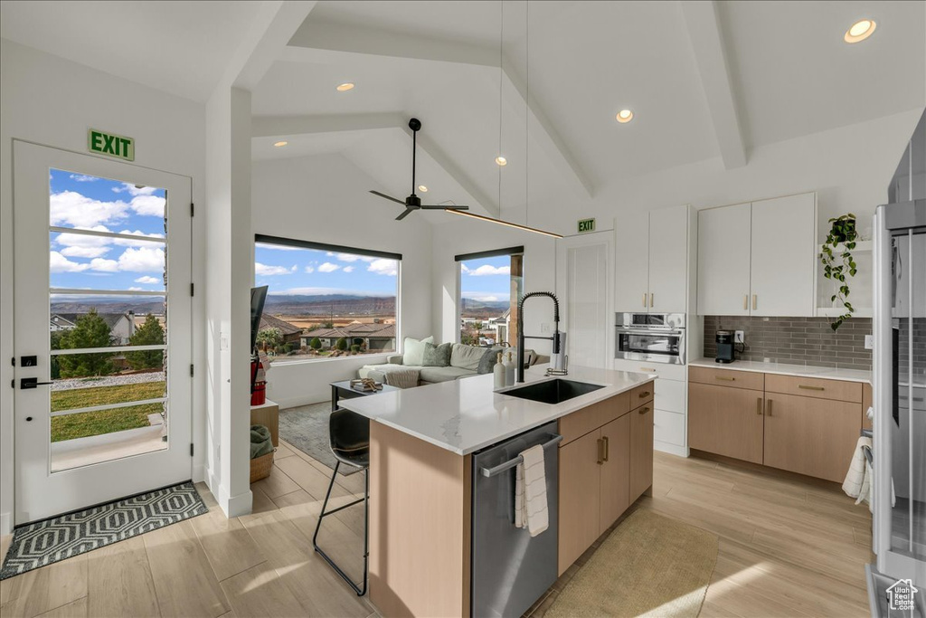 Kitchen with an island with sink, sink, white cabinets, stainless steel appliances, and tasteful backsplash