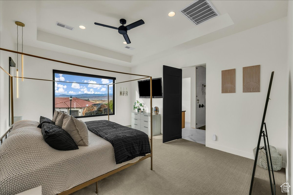 Bedroom featuring a raised ceiling, light carpet, and ceiling fan