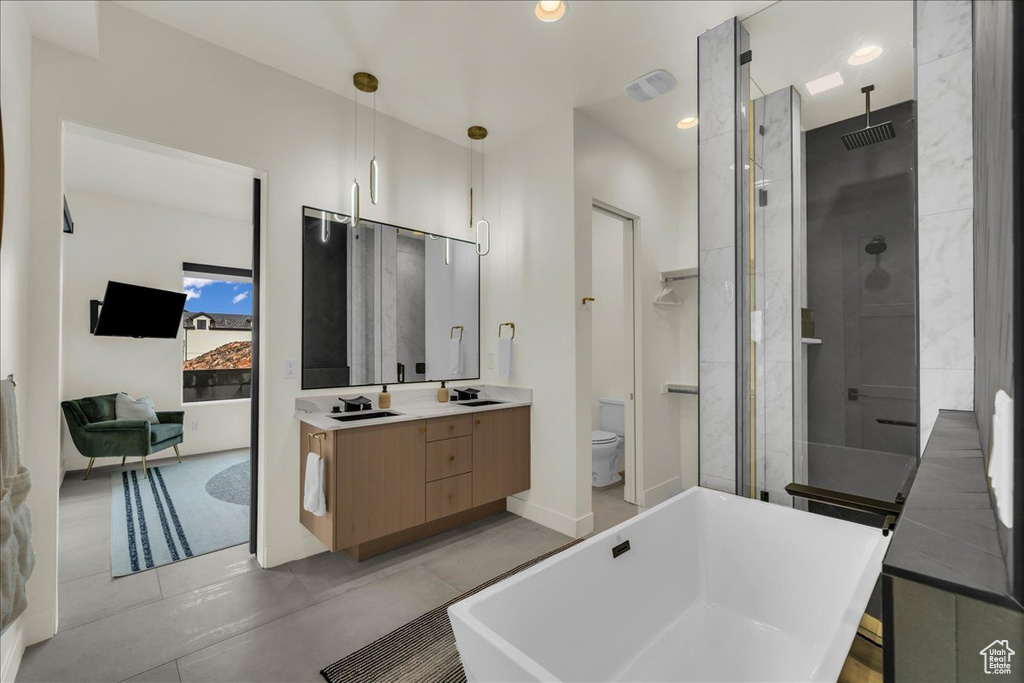 Bathroom featuring toilet, vanity with extensive cabinet space, tile flooring, and an enclosed shower