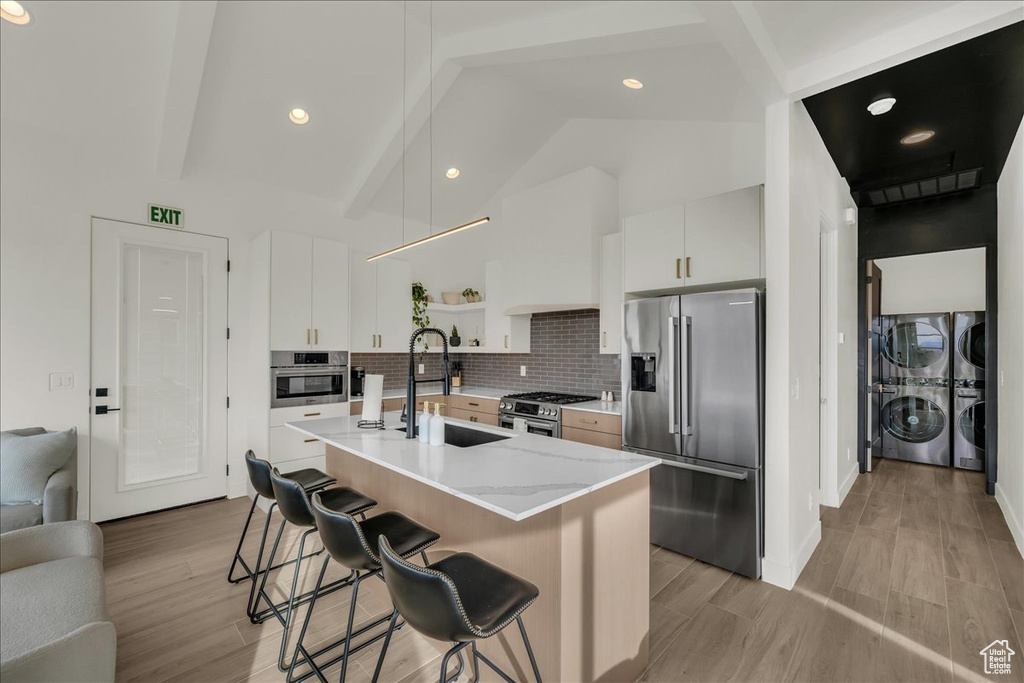 Kitchen featuring sink, white cabinets, appliances with stainless steel finishes, beamed ceiling, and backsplash