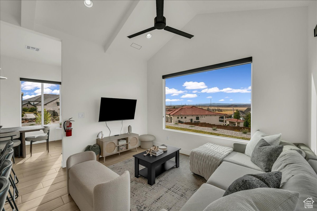 Living room with light hardwood / wood-style flooring, ceiling fan, high vaulted ceiling, and beamed ceiling