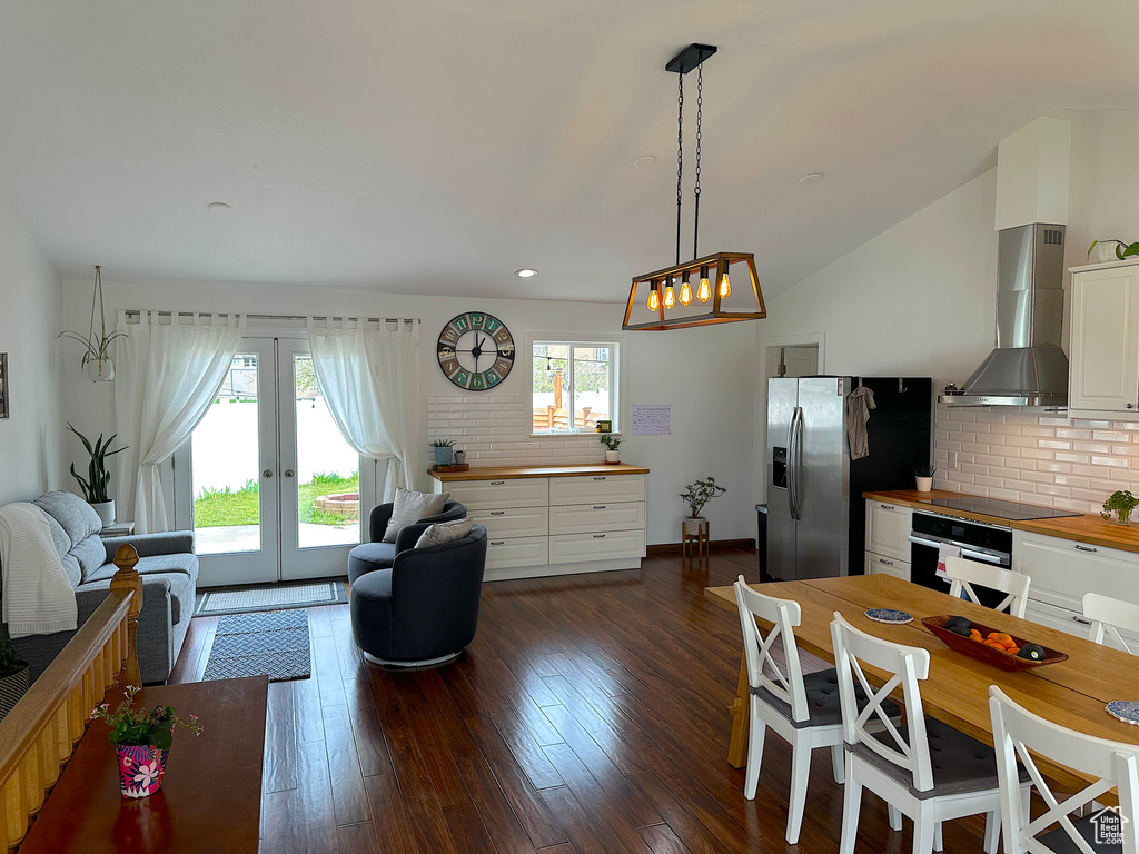 Interior space featuring butcher block counters, backsplash, dark hardwood / wood-style floors, wall chimney range hood, and white cabinetry