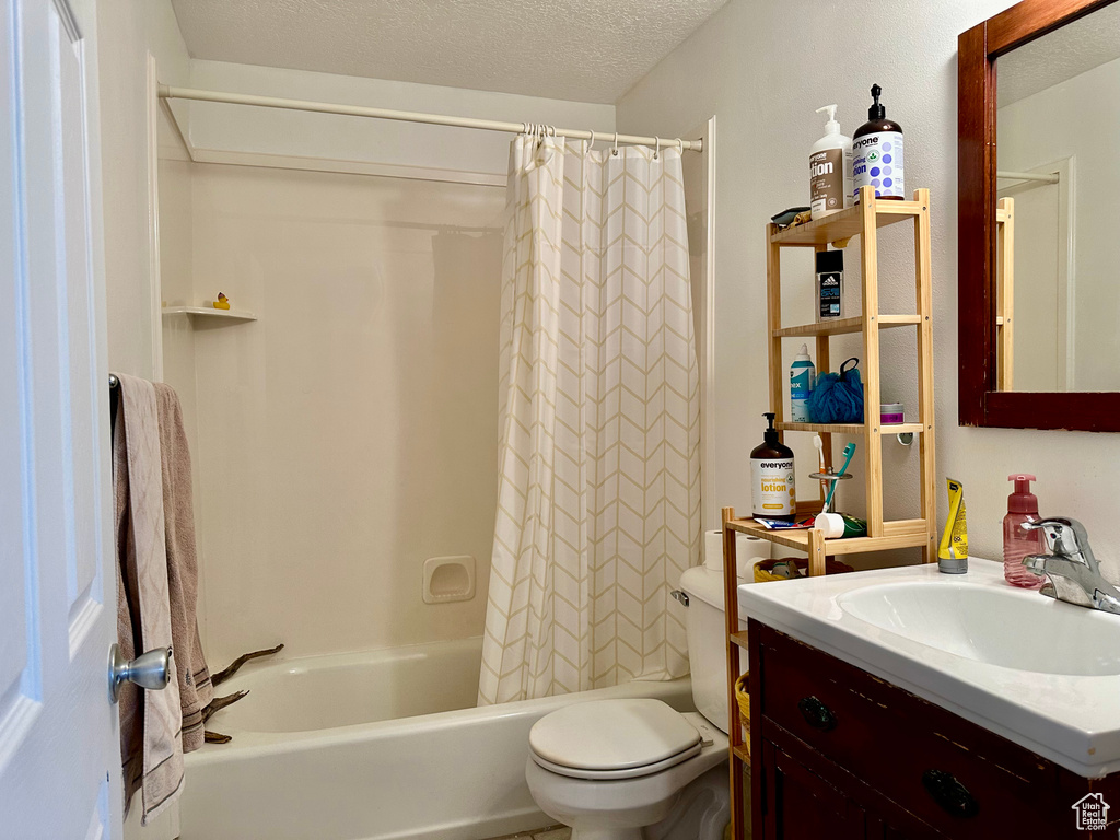 Full bathroom with shower / tub combo, a textured ceiling, large vanity, and toilet