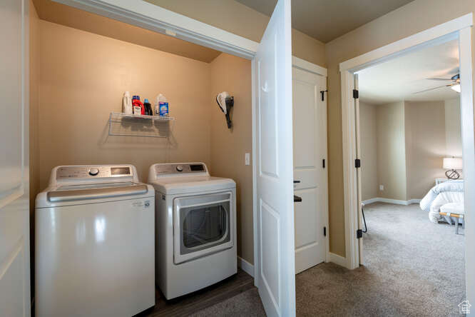 Clothes washing area with washing machine and dryer, dark carpet, and ceiling fan