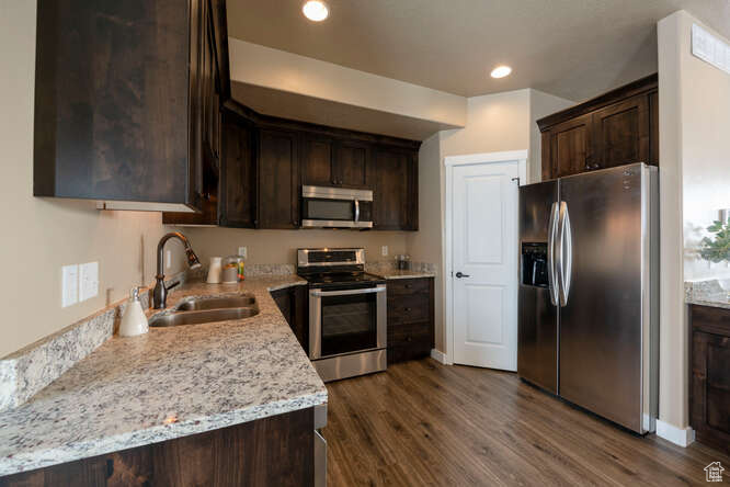 Kitchen featuring dark brown cabinets, dark hardwood / wood-style flooring, sink, and appliances with stainless steel finishes