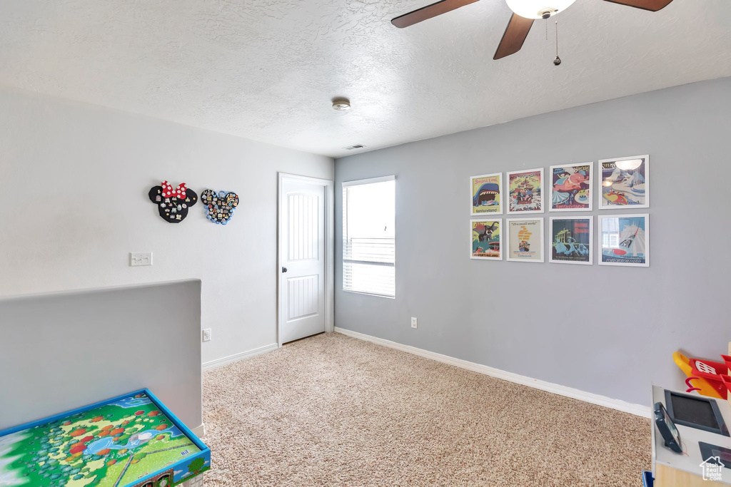 Rec room featuring ceiling fan, a textured ceiling, and light colored carpet