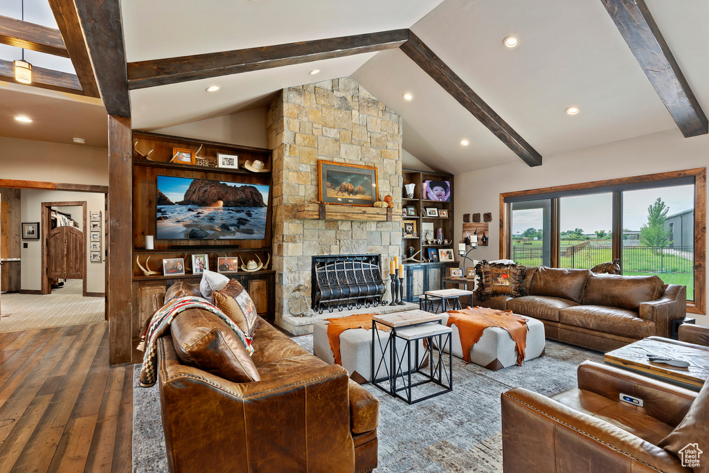 Living room with beamed ceiling, high vaulted ceiling, built in shelves, a stone fireplace, and dark hardwood / wood-style flooring