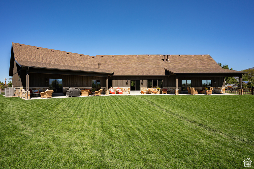 Back of property with a patio area, central AC, outdoor lounge area, and a lawn