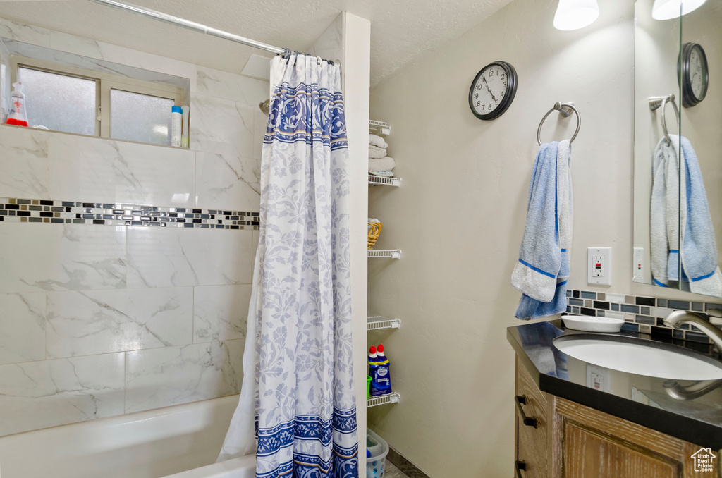 Bathroom with tasteful backsplash, vanity, and shower / tub combo with curtain