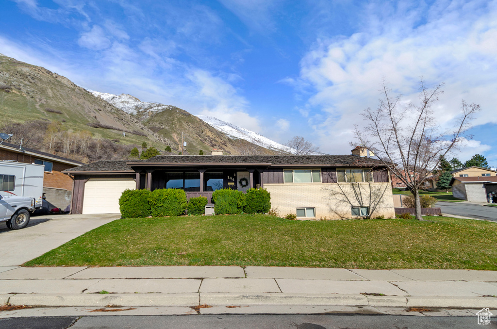 Ranch-style home with a front lawn, a mountain view, and a garage