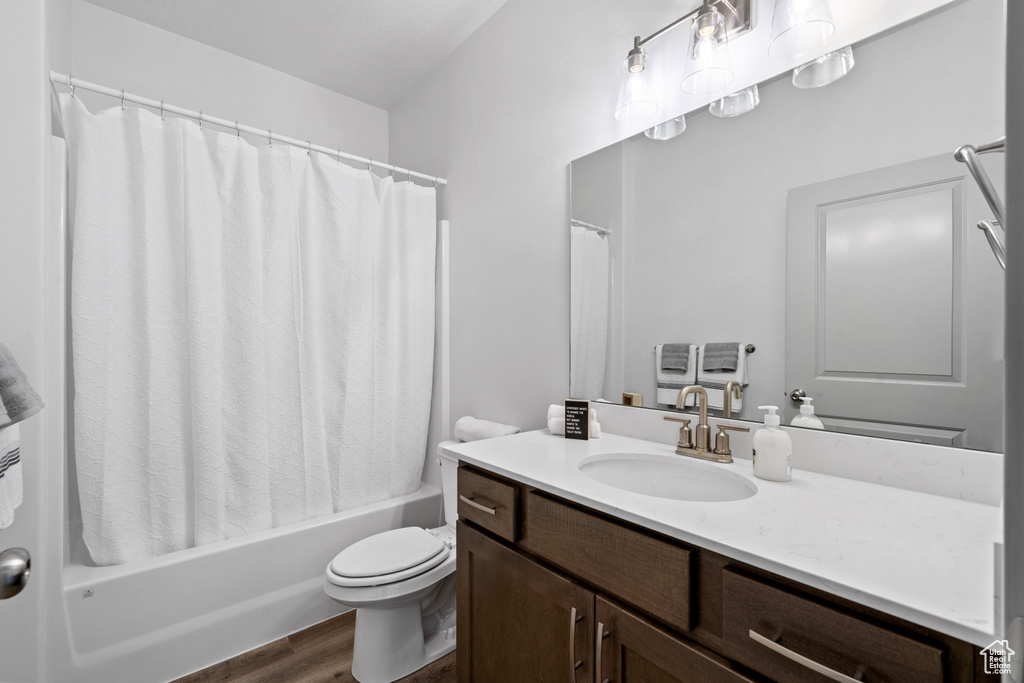 Full bathroom with shower / bath combo, hardwood / wood-style floors, toilet, and oversized vanity