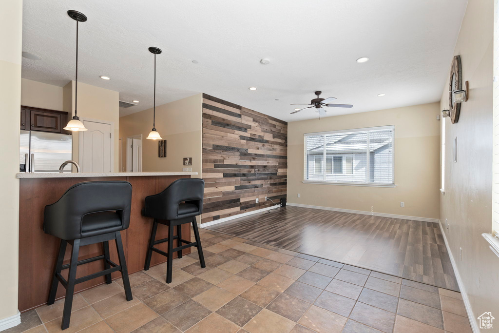 Kitchen with wood walls, stainless steel fridge, ceiling fan, and light tile floors