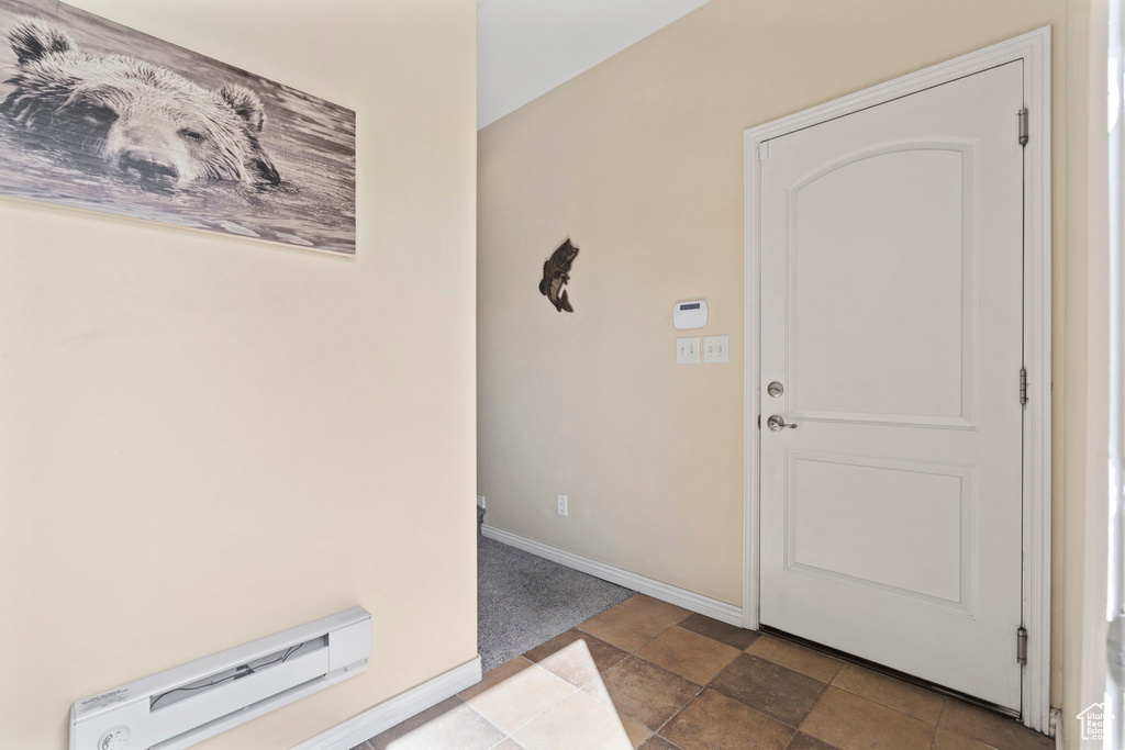 Foyer entrance featuring dark tile flooring and a baseboard heating unit