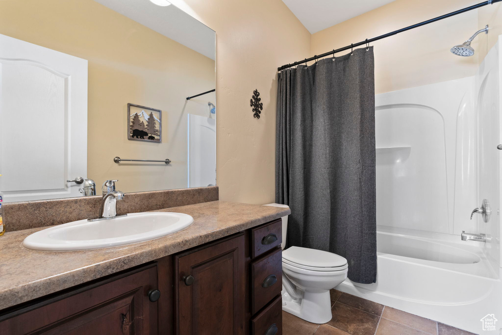 Full bathroom with vanity, tile floors, shower / bath combo with shower curtain, and toilet