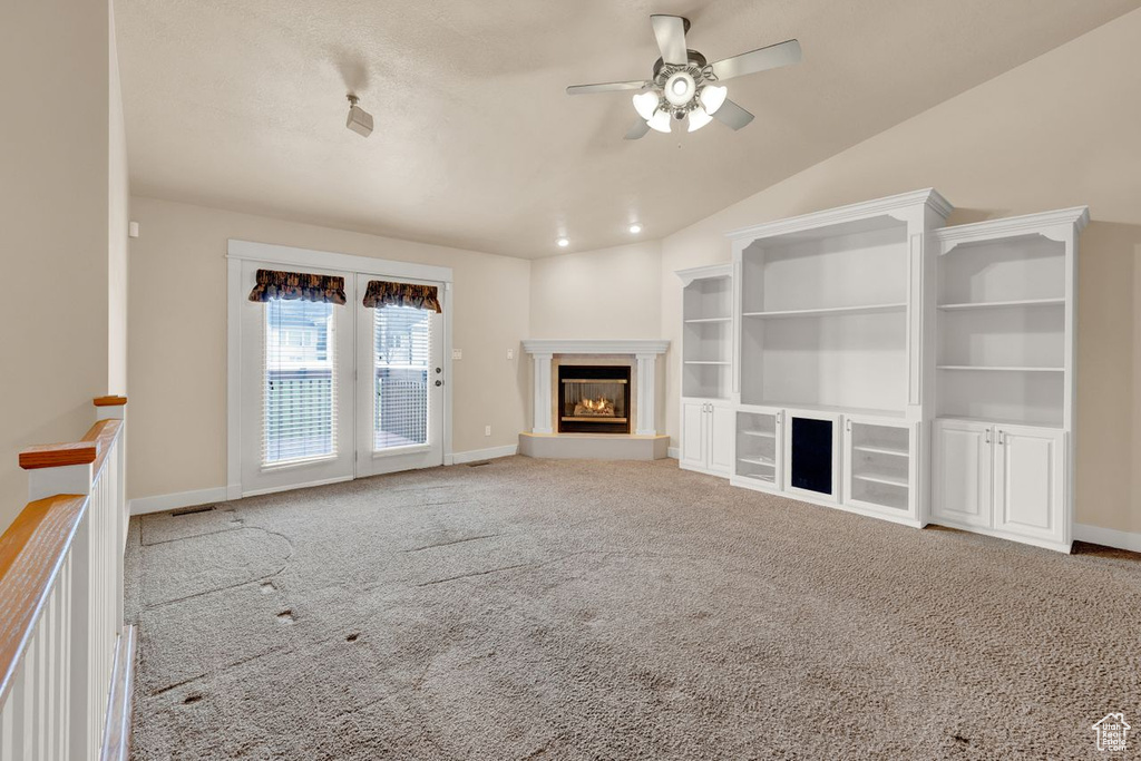 Unfurnished living room with light carpet, vaulted ceiling, and ceiling fan