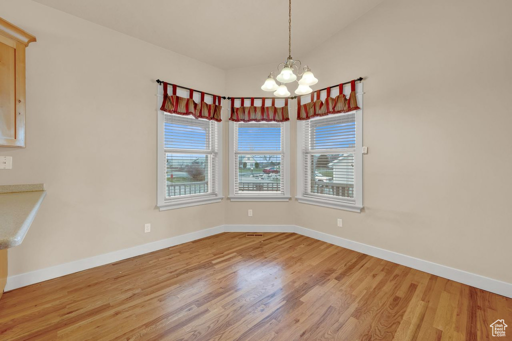 Spare room with light hardwood / wood-style floors and an inviting chandelier