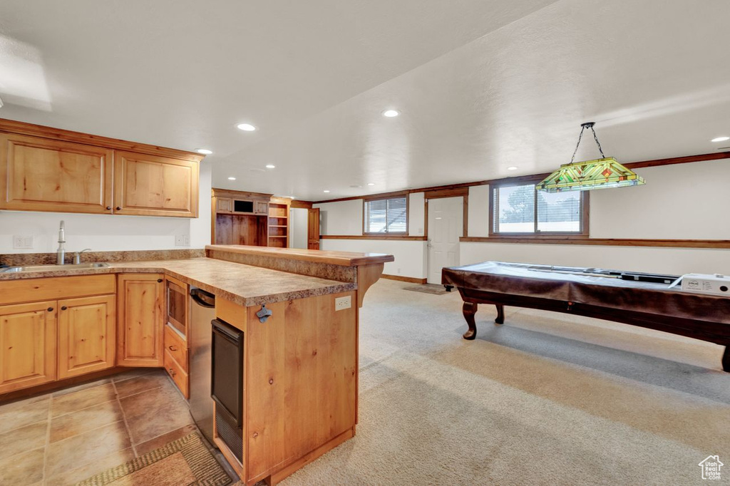 Kitchen with kitchen peninsula, light colored carpet, sink, pool table, and decorative light fixtures