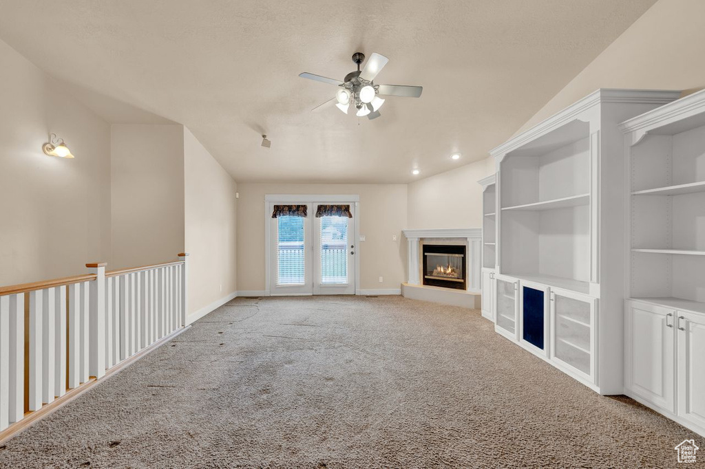Unfurnished living room with light carpet, vaulted ceiling, and ceiling fan