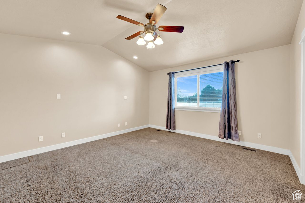 Carpeted spare room with vaulted ceiling and ceiling fan