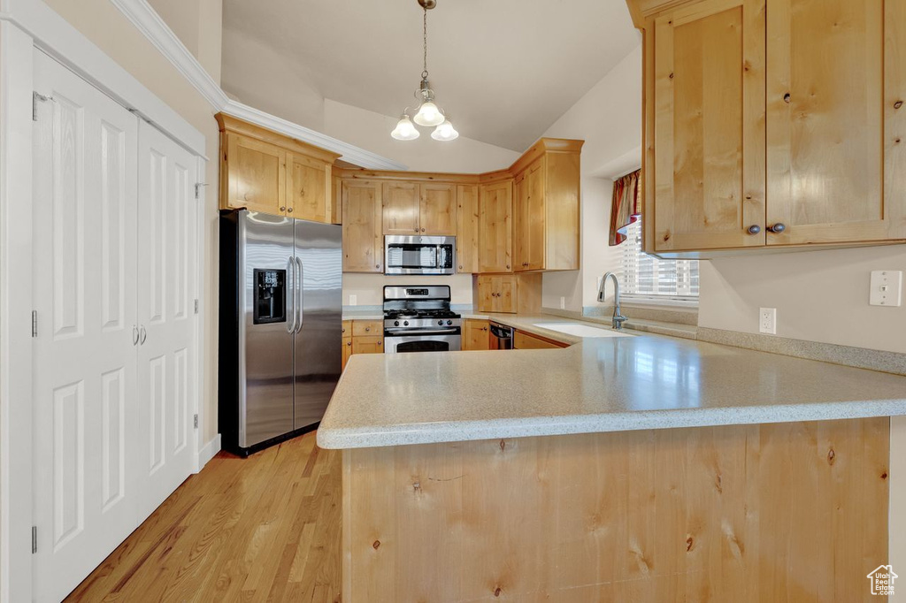 Kitchen featuring kitchen peninsula, sink, light hardwood / wood-style flooring, stainless steel appliances, and decorative light fixtures