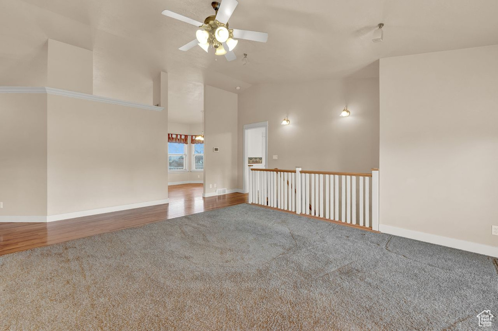 Empty room featuring carpet, ceiling fan, and high vaulted ceiling