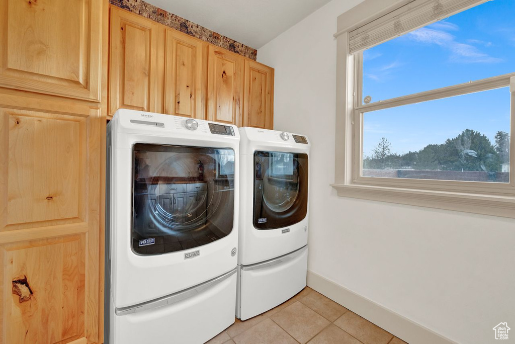 Washroom with light tile flooring, cabinets, and separate washer and dryer