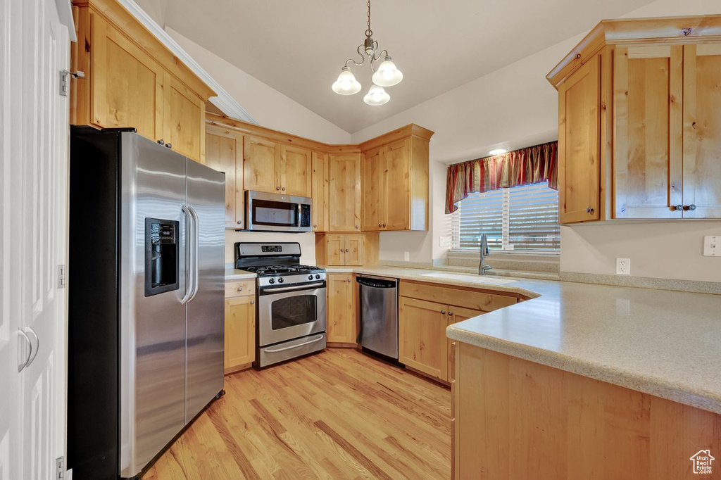 Kitchen with a chandelier, light hardwood / wood-style floors, stainless steel appliances, vaulted ceiling, and sink