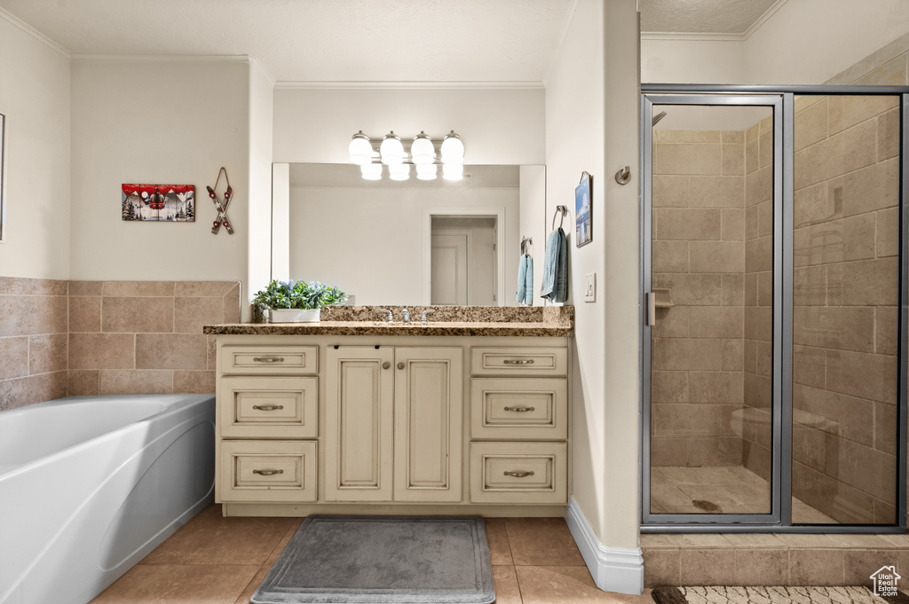 Bathroom featuring crown molding, shower with separate bathtub, tile floors, and vanity