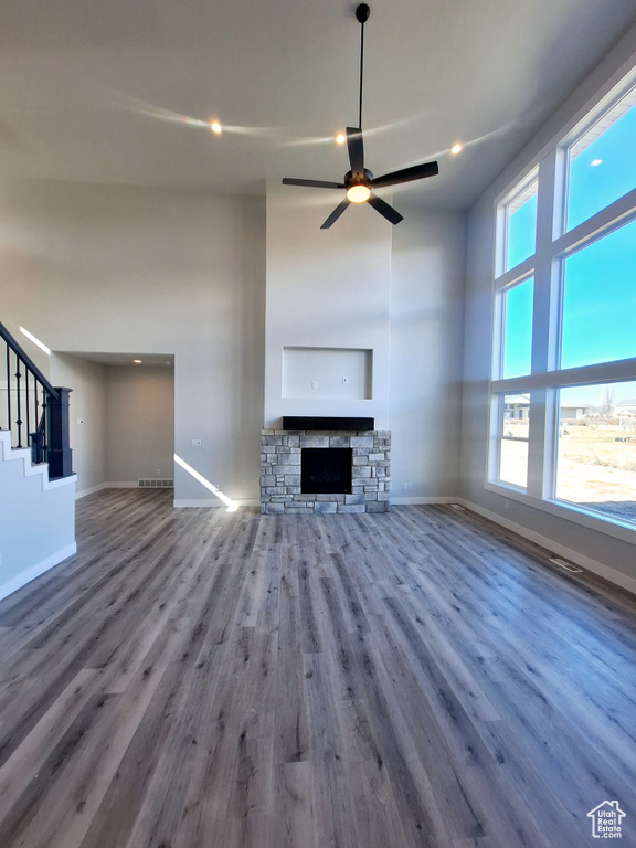 Unfurnished living room with dark hardwood / wood-style flooring, ceiling fan, a fireplace, and a healthy amount of sunlight